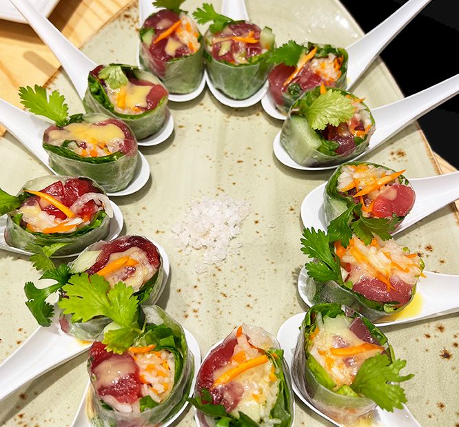 Fresh Vietnamese-style spring rolls with cucumber leaves, shrimp, cured meat, and cilantro served on a platter, .